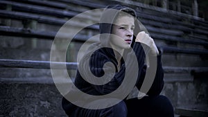 Upset boy feels depression, sitting on stadium tribune, loneliness and sorrow