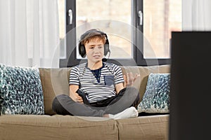 Upset boy with gamepad playing video game at home