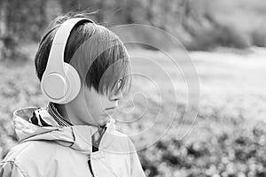 Upset boy with headphones on the walk. Lifestyle, childhood and emotions