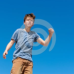 Upset boy raising fist outdoors.