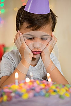 Upset boy sitting with birthday cake