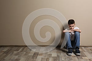Upset boy sitting on floor at color wall