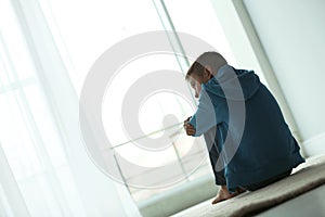 Upset boy sitting near window. Space for text