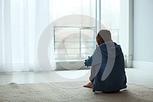 Upset boy sitting near window. Space for text