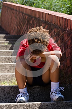 Upset boy sitting on staircase in the boot camp