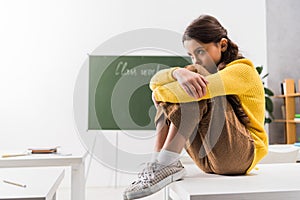 Upset and bullied schoolgirl sitting on