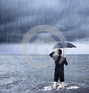 Upset business man holding a umbrella with cloudburst