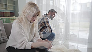 Upset caucasian couple siting apart on couch. Husband and wife having relationship problems. Marriage, break-up