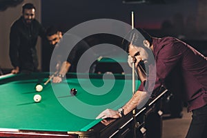 upset caucasian man with cue beside pool table at bar