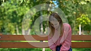 Upset caucasian woman sitting alone park bench, problem hopelessness, sadness