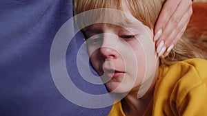 Upset child little girl kid crying with tears flowing down on cheek, toddler lies on mother at home