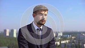 Upset company employee sitting outdoors, occupational burnout, unemployment