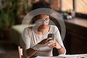 Upset confused african woman holding cellphone having problem with phone