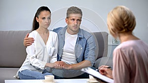 Upset couple holding hands on psychologist consultation, saving family attempt