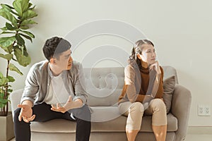 Upset couple at home. Handsome man and beautiful young woman are having quarrel. Sitting on sofa together. Family problems