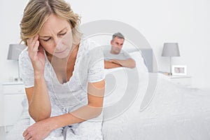 Upset couple sitting on opposite ends of bed after a fight