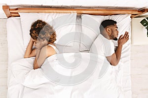 Upset couple sleeping separately on their bed