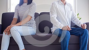 Upset couples sit separately on the sofa in the living room after an argument. The problem of love after marriage which leads to