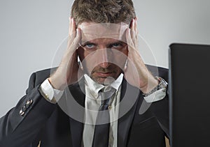 Upset and depressed businessman at office desk - young unhappy man working frustrated suffering stress and depression as employee