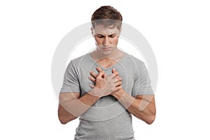 Upset despaired attractive millennial european male suffering from chest pain, presses hand to sore spot