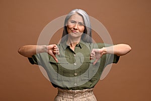 Upset disappointed asian middle age woman showing double thumbs down, refusing, criticizing with dislike gesture