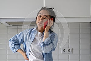 Upset dissatisfied young Asian woman talking on phone arguing by mobile at home