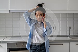 Upset dissatisfied young Asian woman talking on phone arguing by mobile at home