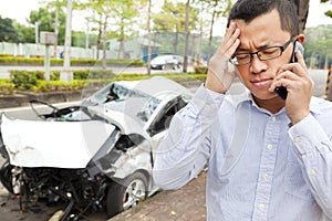 Upset driver talking on mobile phone with crash car