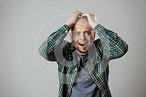 Upset emotive man grab his head over beige background.
