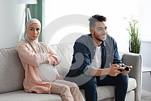 Upset Expectant Muslim Woman Sitting Offended To Husband That Playing Video Games