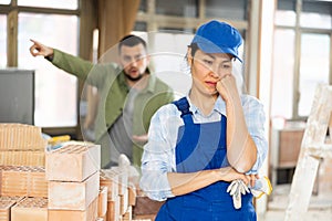 Upset female builder in building under construction with angry client