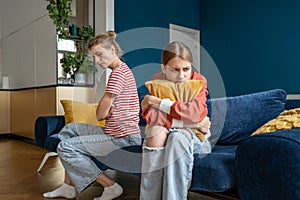 Upset frustrated mother and teenage daughter ignoring each other after quarrel at home, not talking