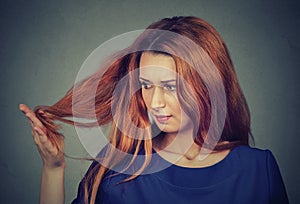 Upset frustrated young woman surprised she is losing hair, noticed split ends