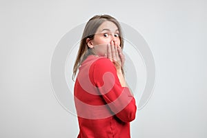 Upset girl in red sweater holding her hands on her chin being scared after what she did.