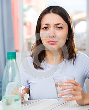 Upset girl suffering from troubles at table with bottled water