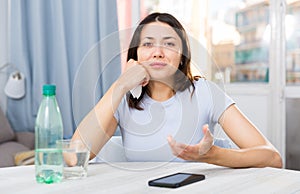 Upset girl suffering from troubles at table with bottled water