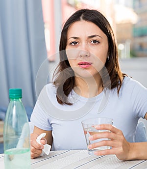 Upset girl suffering from troubles at table with bottled water