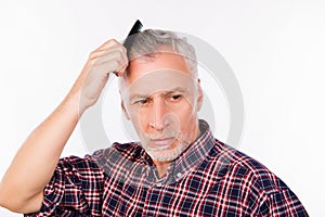Upset gray aged man combing his hair