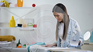 Upset housewife burning hole on blouse during ironing, lack of experience