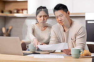 Upset japanese husband and wife checking their expenses