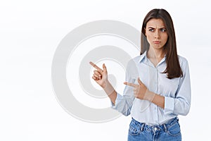 Upset or jealous cute brunette woman in blouse pouting, sulking with regret, being offended not invited to cool office