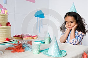 upset little african american girl sitting alone at birthday
