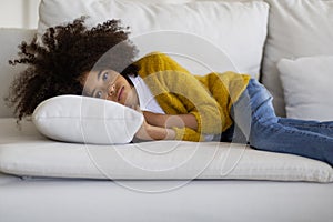 Upset little black girl lying on couch at home