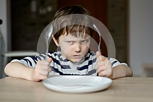 Upset little boy waiting for dinner