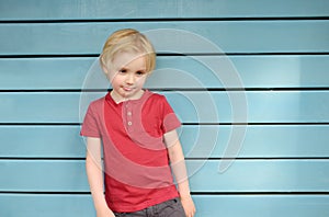 Upset little boy wearing red t-shirt standing on blue background. Expression on child face is sense of grievance and disbelief