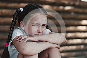 Upset little girl sitting near the wall