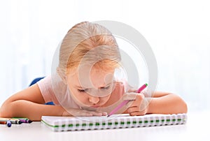 Upset little left-handed girl drawing at table