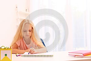 Upset little left-handed girl drawing at table