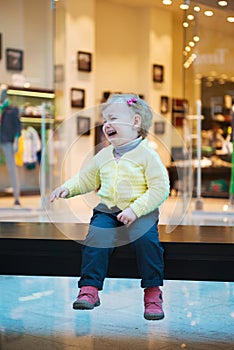 Lost girl sitting on bench in mall