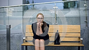 Upset lonely business woman sitting on bench, worried about dismissal from work